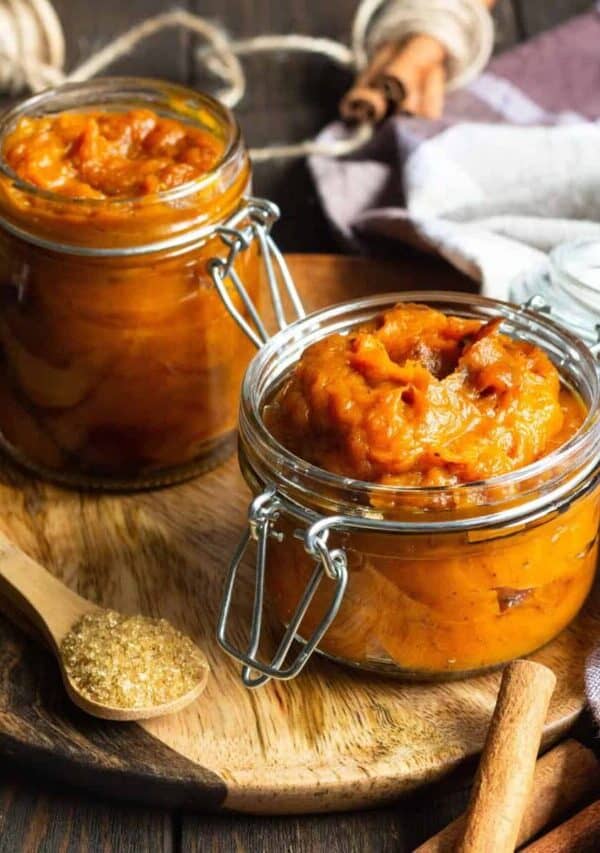 Two glass jars of Pumpkin Butter on a wooden cutting board