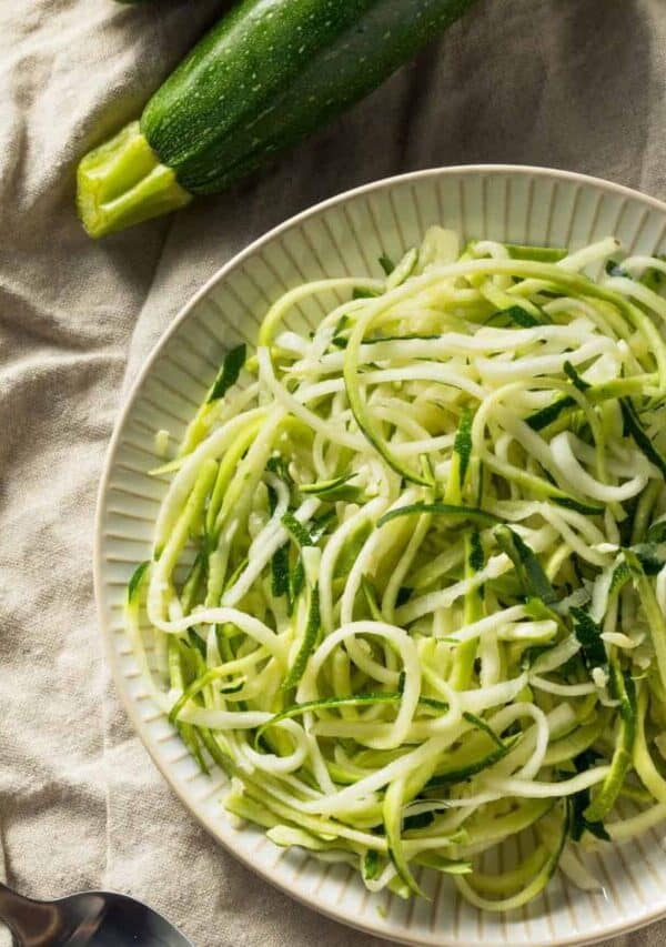 Overhead image of zucchini noodles on a cream colored plate