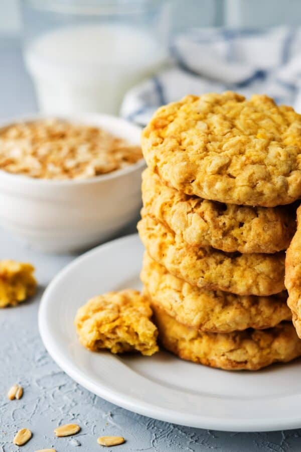 Pumpkin Oatmeal Cookies on a white plate with oats and milk in the background