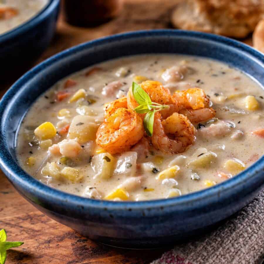 Close up image of Shrimp and Corn Soup in a blue bowl on on a rustic surface