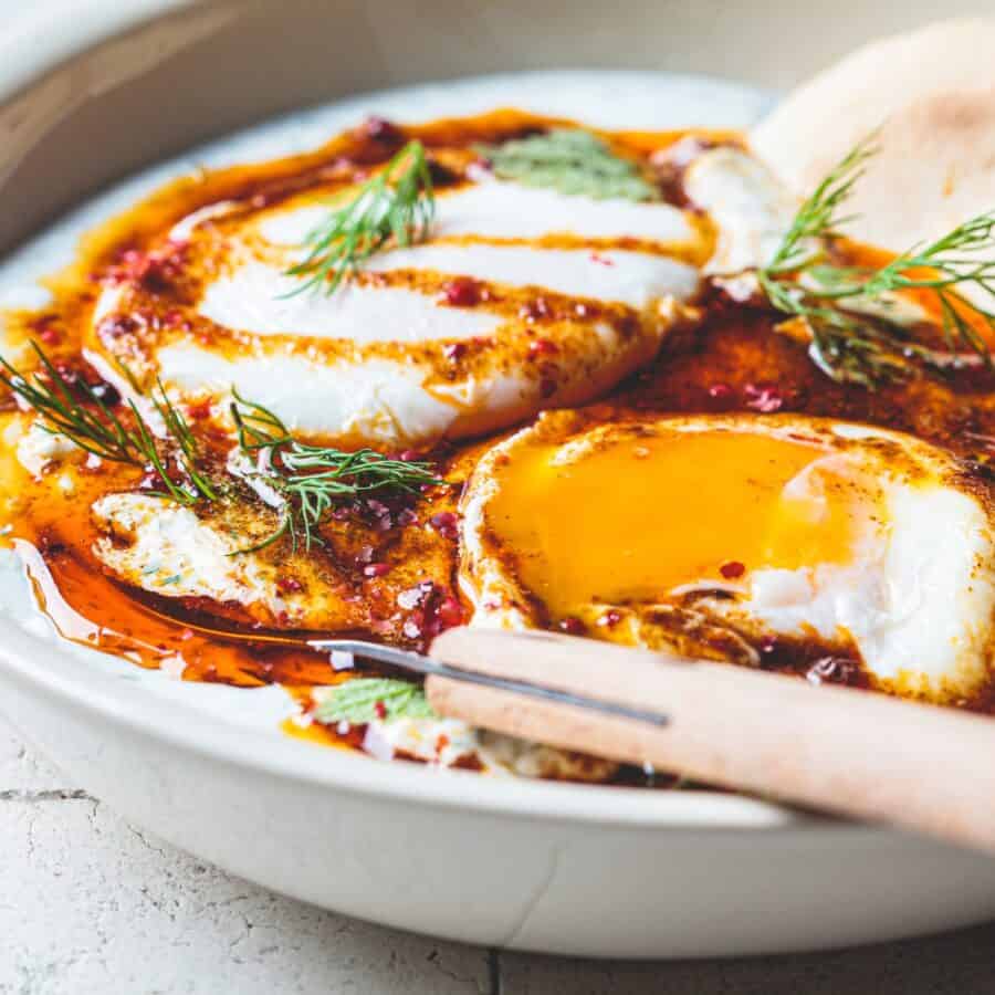 Close up image of Turkish Eggs in a bowl with a knife