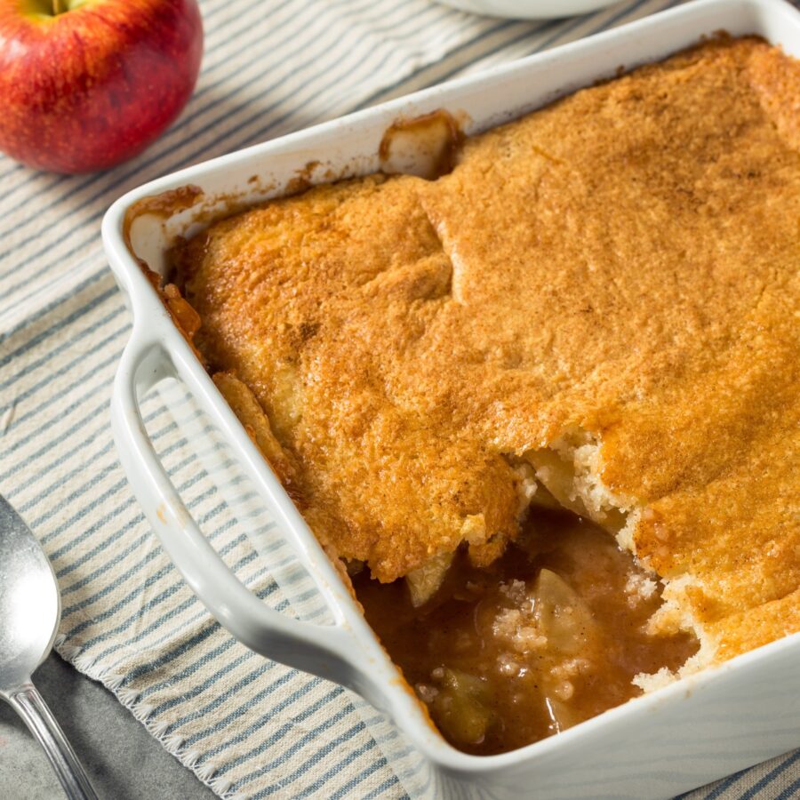 Overhead image of Apple Cobbler in a white dish with a serving taken out of it