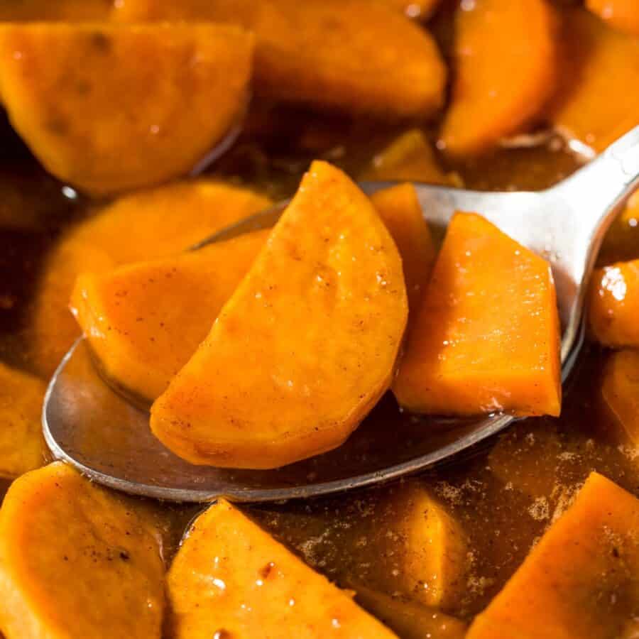 Close up image of a spoon in a dish of candied yams