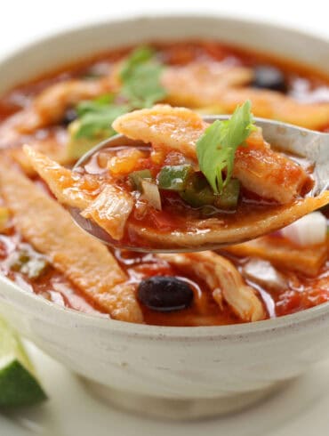 A spoon in a white bowl of Crock Pot Chicken Tortilla Soup