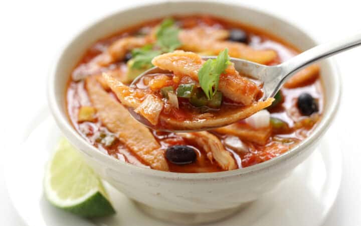 A spoon in a white bowl of Crock Pot Chicken Tortilla Soup