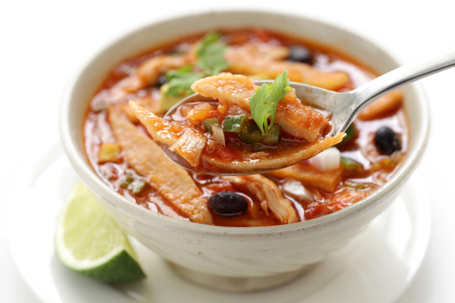 A spoon in a white bowl of Crock Pot Chicken Tortilla Soup