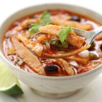 A spoon in a white bowl of Crock Pot Chicken Tortilla Soup