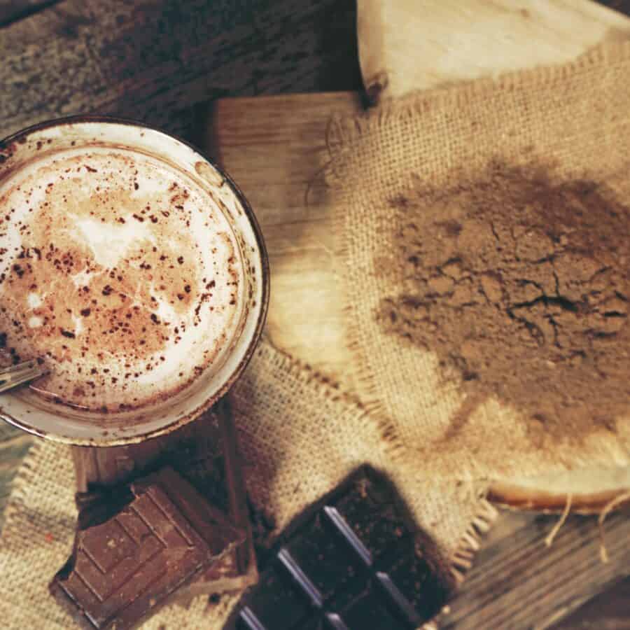 Overhead image of hot chocolate mix spilled on a table next to a mug of hot chocolate