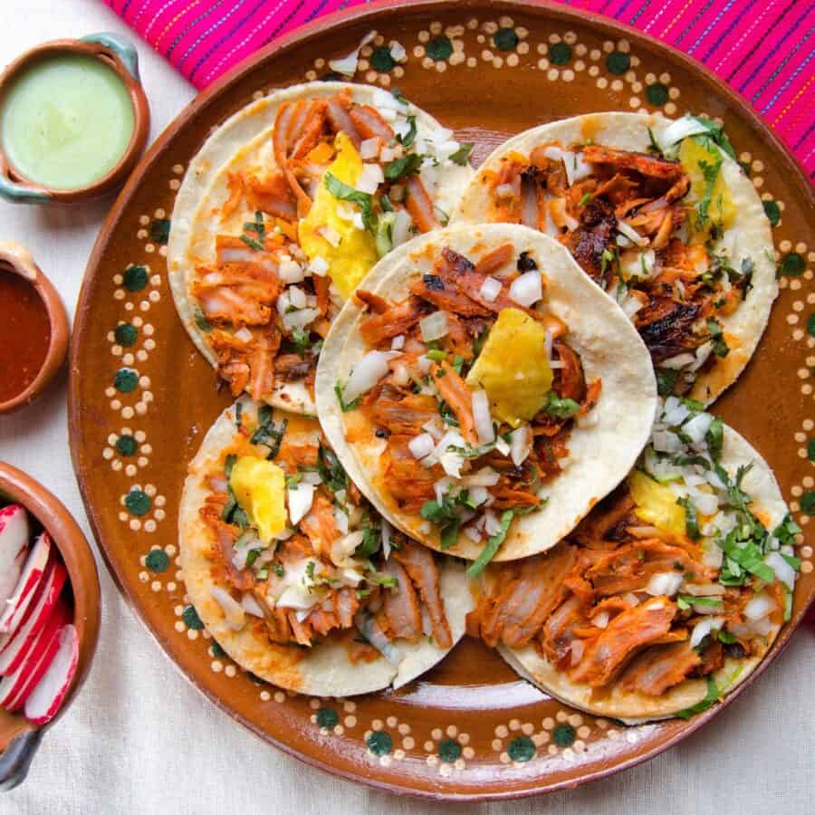 Overhead image of five Pork Al Pastor tacos on a decorative plate