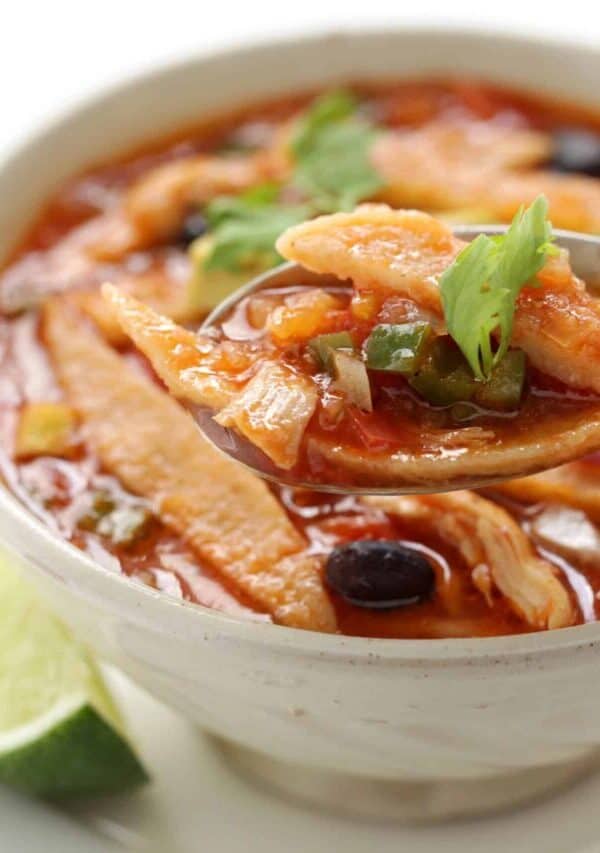 A spoon in a white bowl of Crock Pot Chicken Tortilla Soup