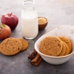 Applesauce Cookies in a white bowl with a glass of milk and more cookies beside it