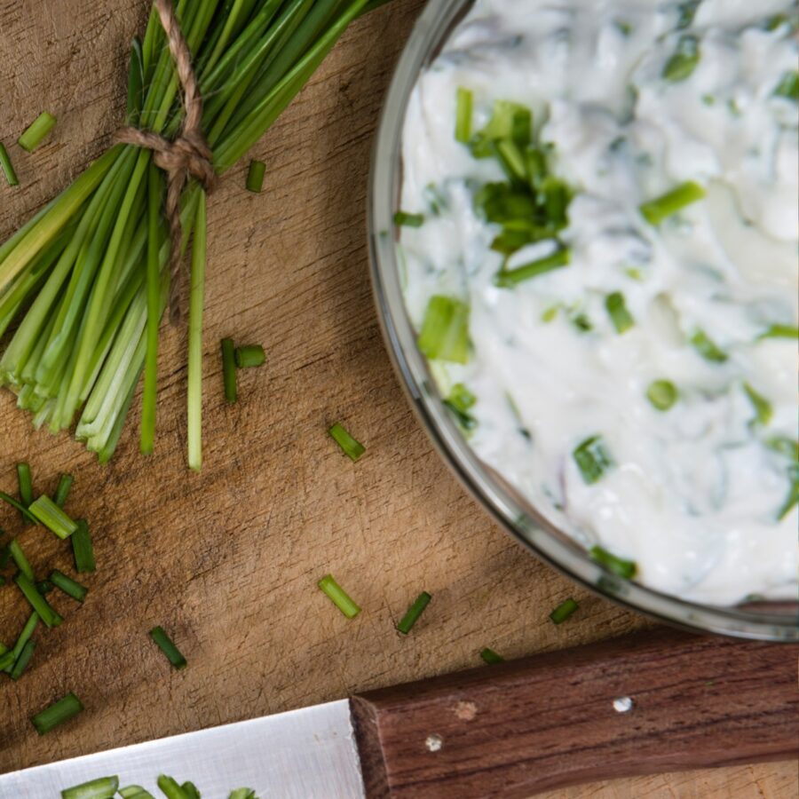 overhead image of cream cheese dip on a wooden surface with herbs