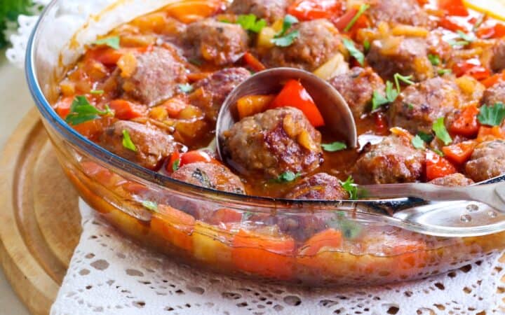 Hawaiian meatballs in a glass bowl being served with a spoon