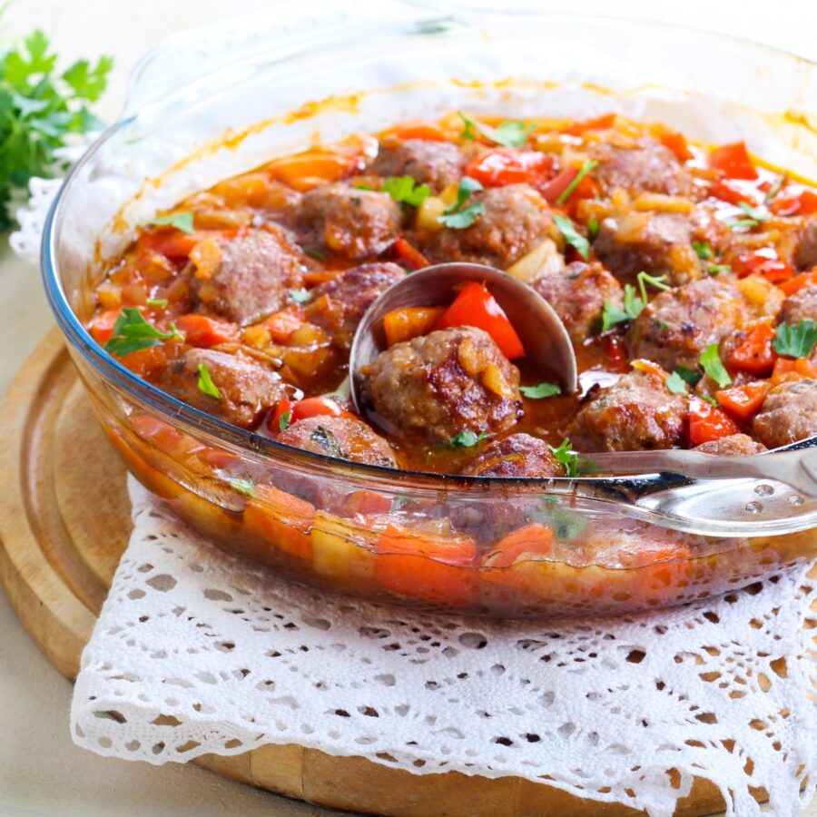 Hawaiian meatballs in a glass bowl being served with a spoon