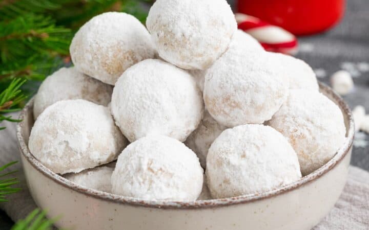 Close up image of Snowball Cookies in a bowl with Christmas decor surrounding it