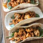 Overhead image of cauliflower tacos on a wooden cutting board