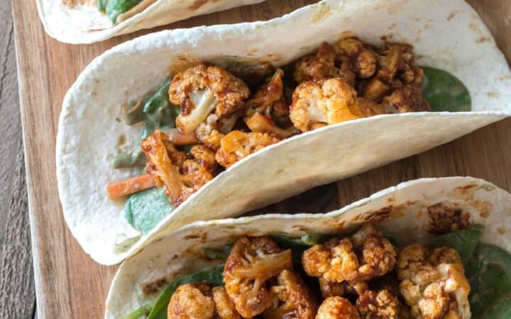 Overhead image of cauliflower tacos on a wooden cutting board