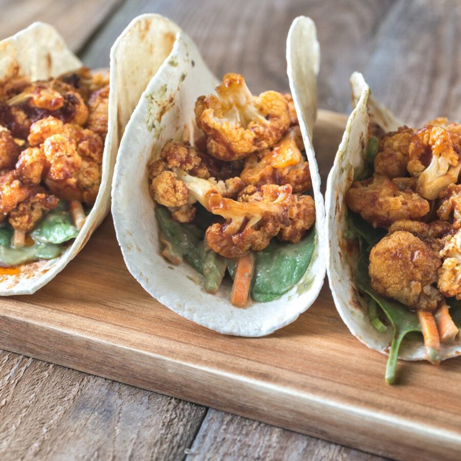 Close up image of roasted cauliflower tacos on a wooden cutting board