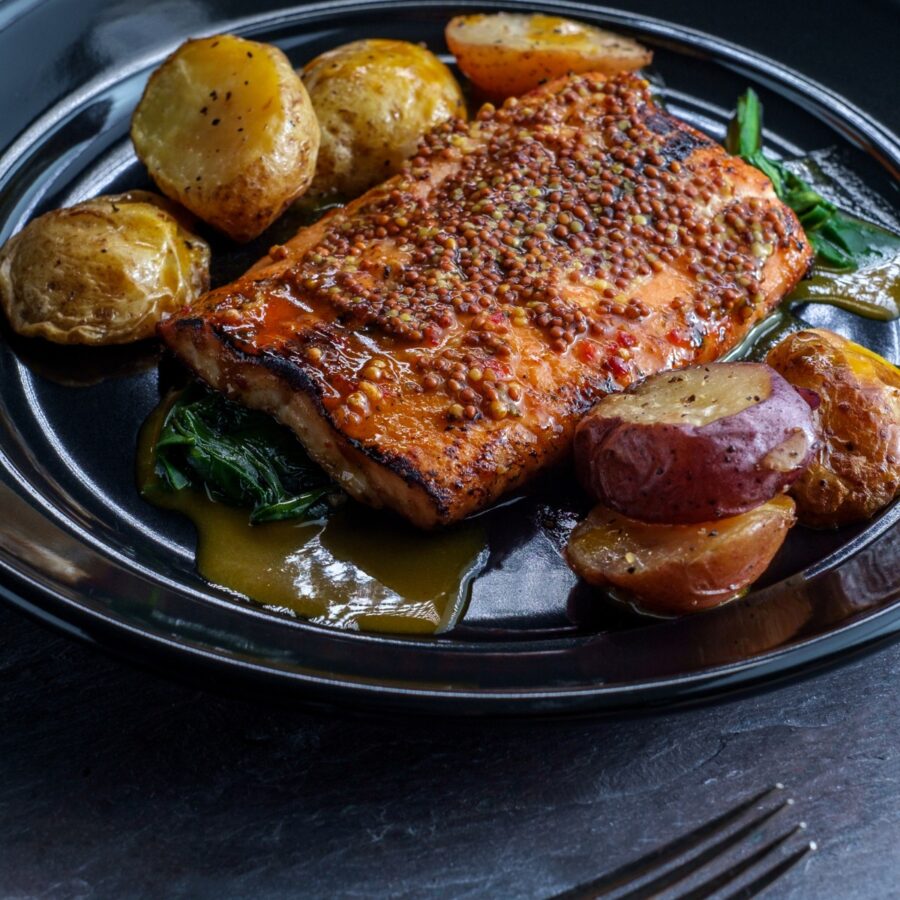 Dijon Salmon on a dark plate with potatoes and greens