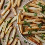 Close up image of Oven Baked Fries in a bowl and on brown parchment paper next to it - 8