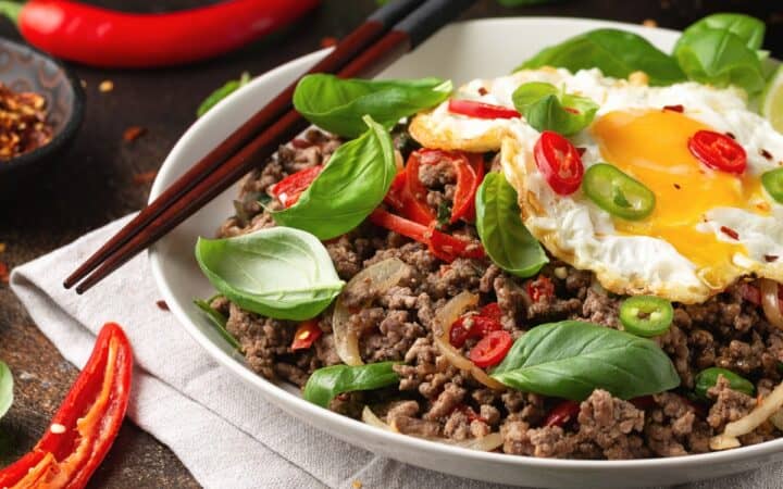 pad kra pao in a white bowl with chopsticks