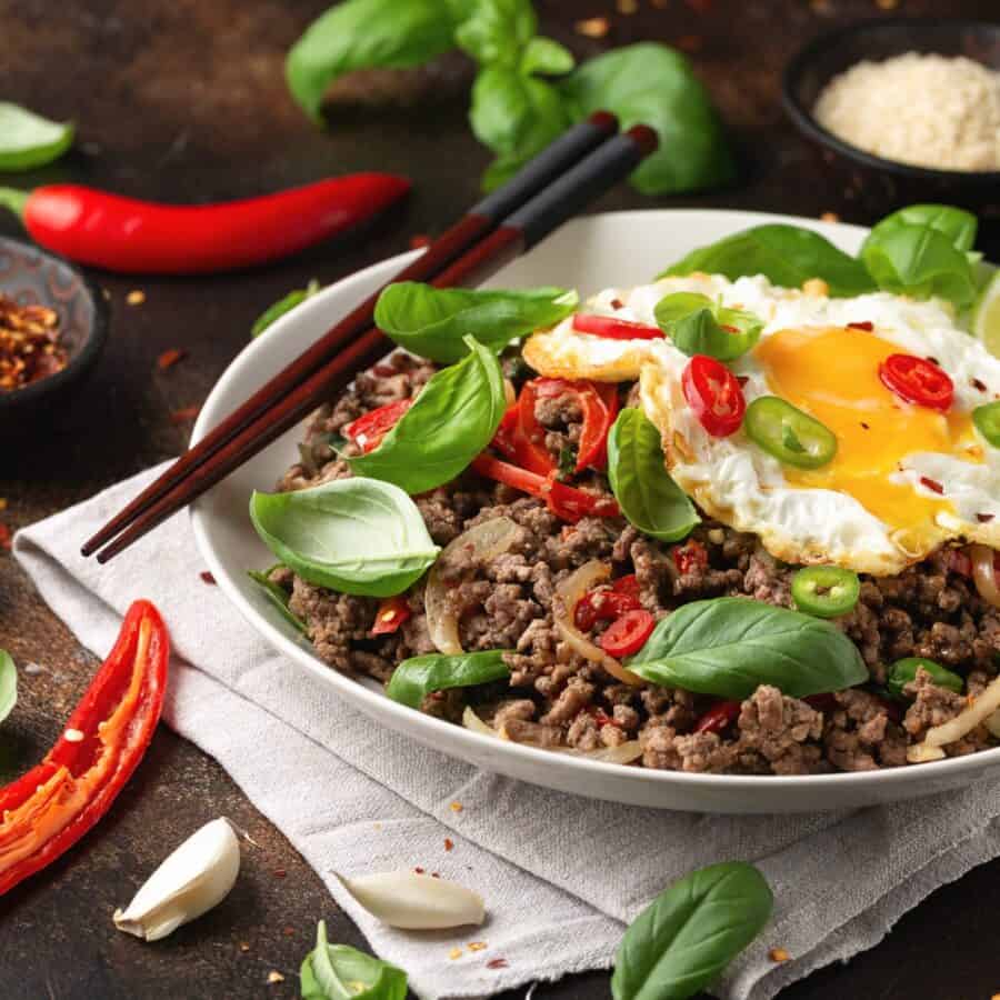 pad kra pao in a white bowl with chopsticks