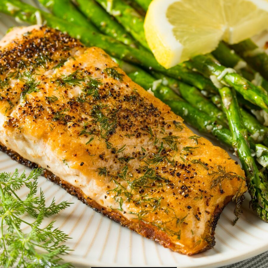 Close up image of Pan Seared Salmon on a white plate with asparagus and dill