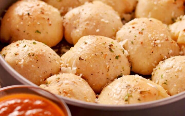 Pizza Balls in a round baking dish with a side of marinara dipping sauce