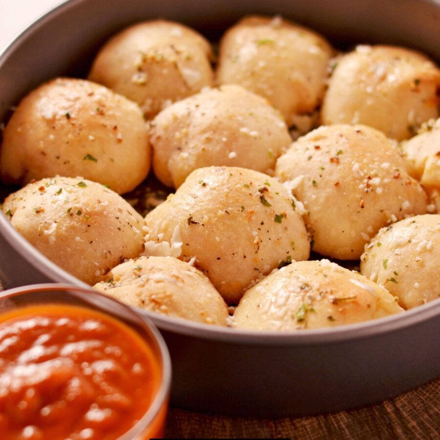 Pizza Balls in a round baking dish with a side of marinara dipping sauce