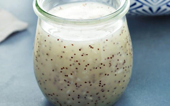 Poppyseed Dressing in a glass jar on a blue surface