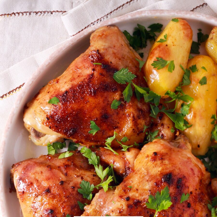 Close up image of roasted chicken and potatoes on a white plate