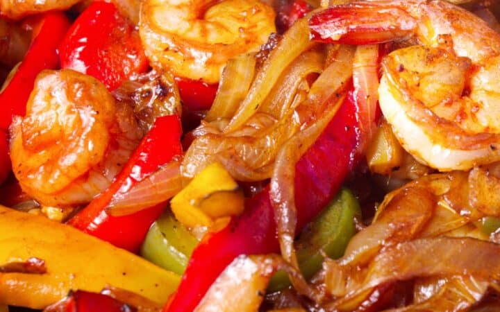 Image of roasted onions, peppers, and shrimp to fill Sheet Pan Shrimp Fajitas