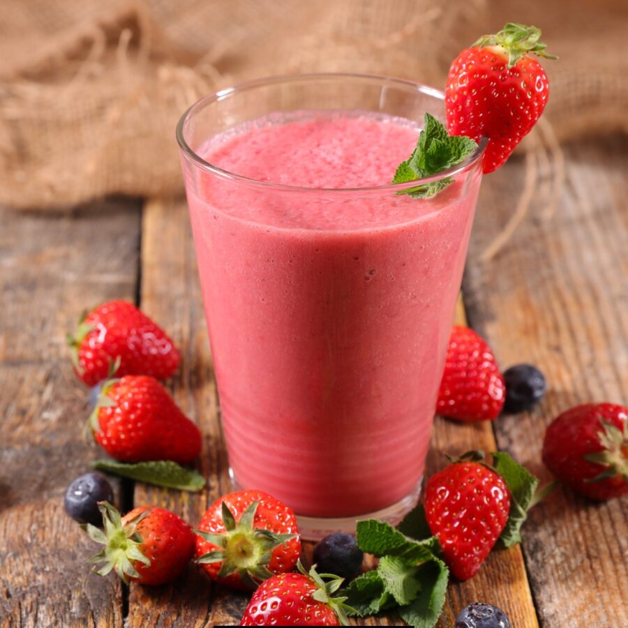 Strawberry Smoothie in a glass with berries surrounding it