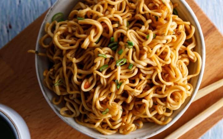 Overhead image of Teriyaki Noodles in a bowl on a wooden cutting board