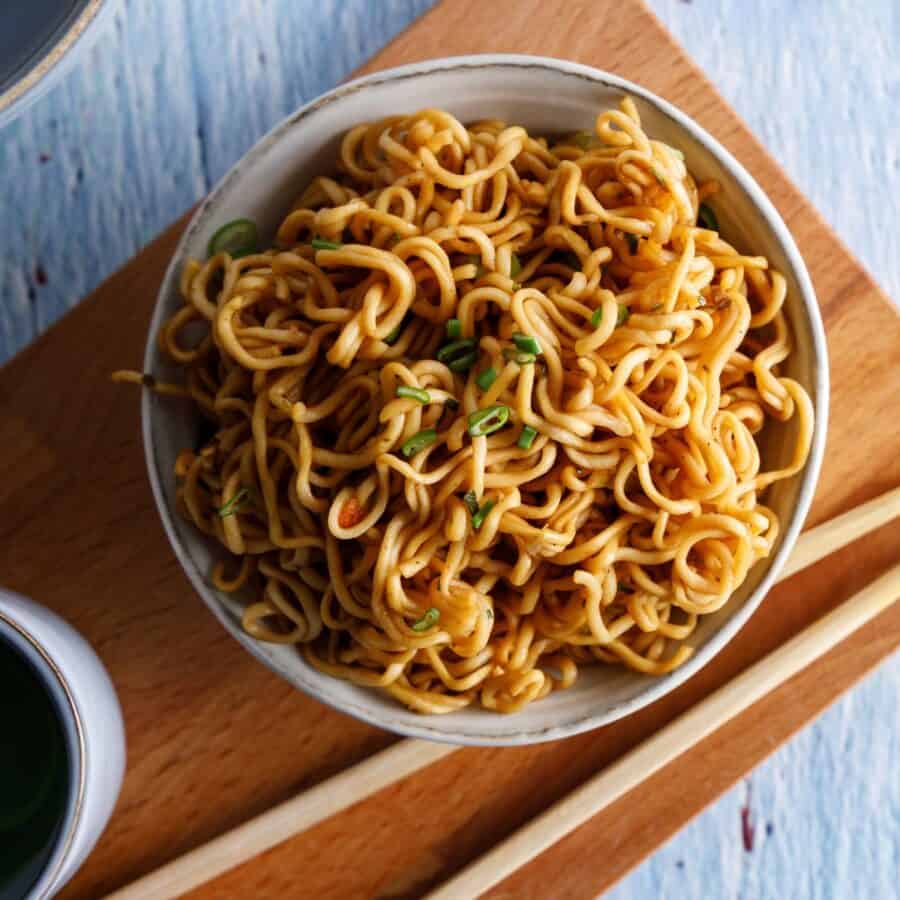 Overhead image of Teriyaki Noodles in a bowl on a wooden cutting board