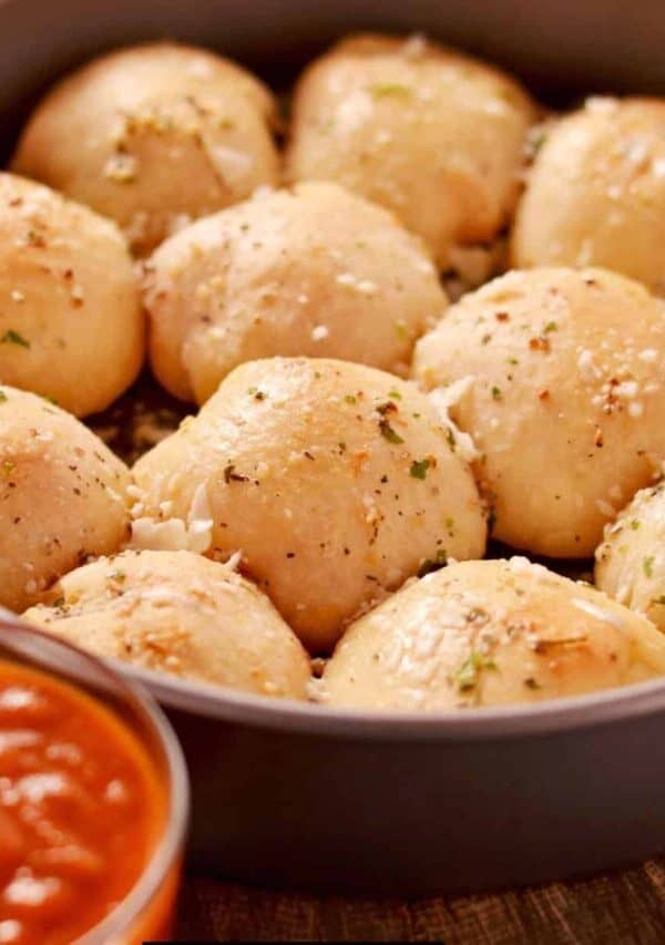 Pizza Balls in a round baking dish with a side of marinara dipping sauce