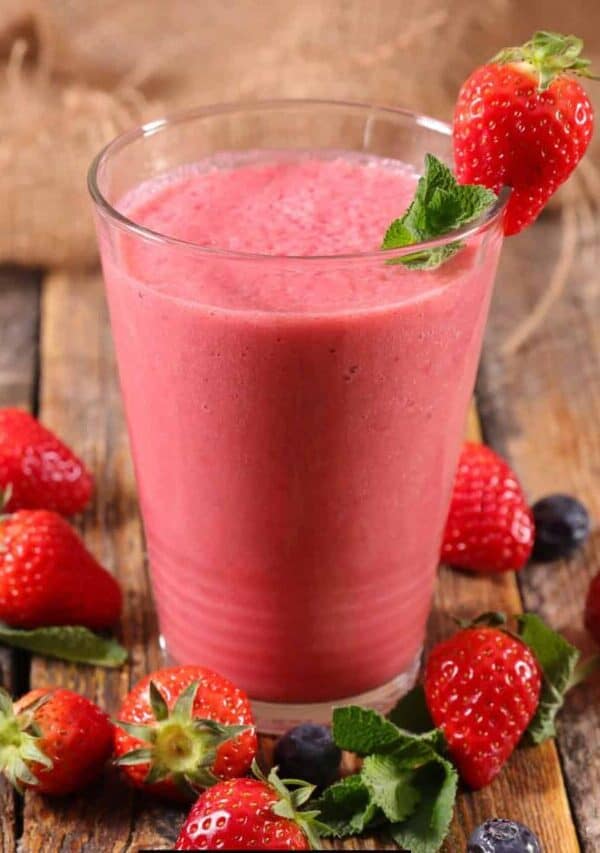 Strawberry Smoothie in a glass with berries surrounding it