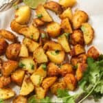 Overhead image of air fryer breakfast potatoes on a white plate with herbs - 8