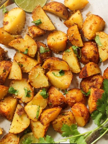 Overhead image of air fryer breakfast potatoes on a white plate with herbs