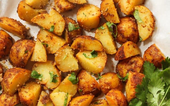 Overhead image of air fryer breakfast potatoes on a white plate with herbs