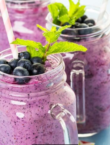 Close up image of three glass mugs full of blueberry smoothie