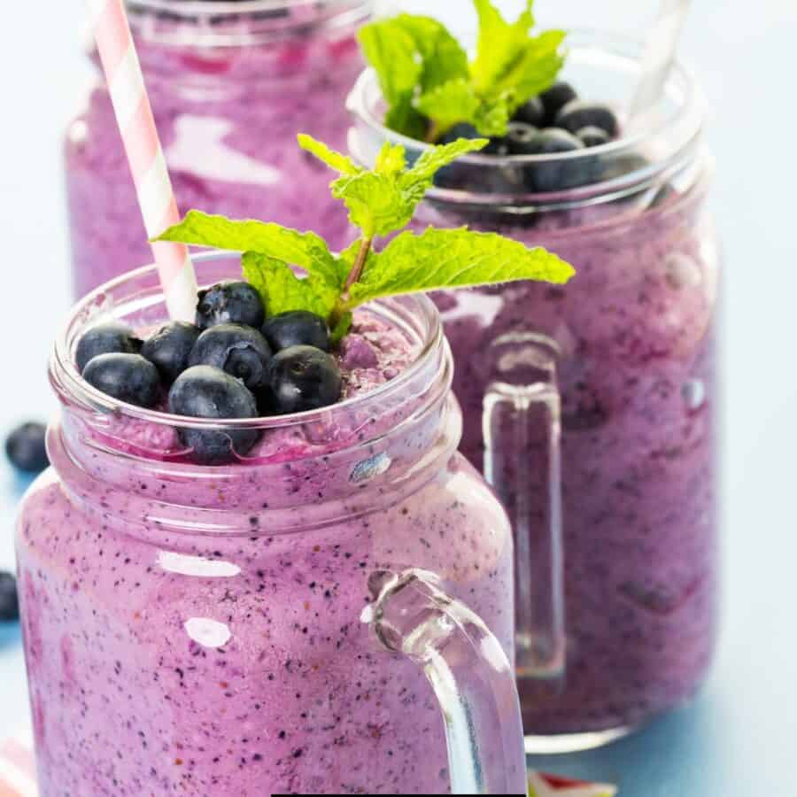 Close up image of three glass mugs full of blueberry smoothie