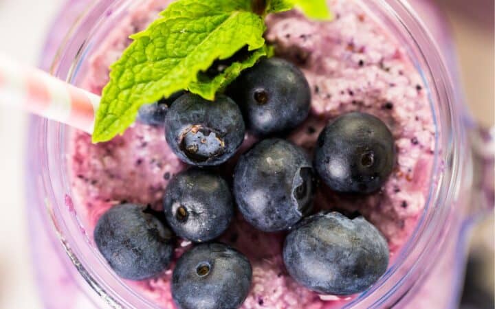 overhead image of a blueberry smoothie with mint and blueberry garnish