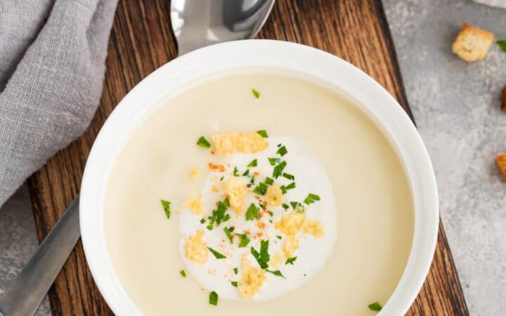 Overhead image of cauliflower cheese soup in a white bowl