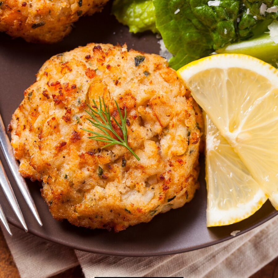 Overhead image of fish cakes on a plate with lemon and broccoli