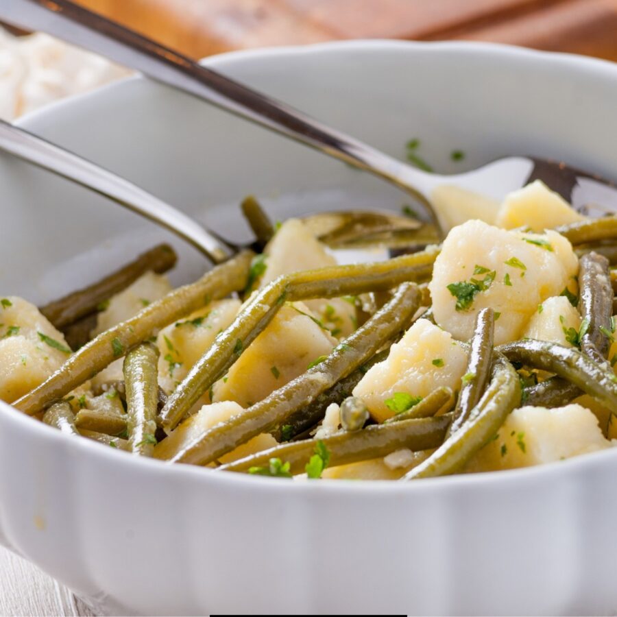 Green Beans and Potatoes in a white bowl with a serving spoon