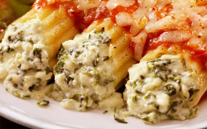 Close up image of three pieces of cheese manicotti covered in marinara sauce