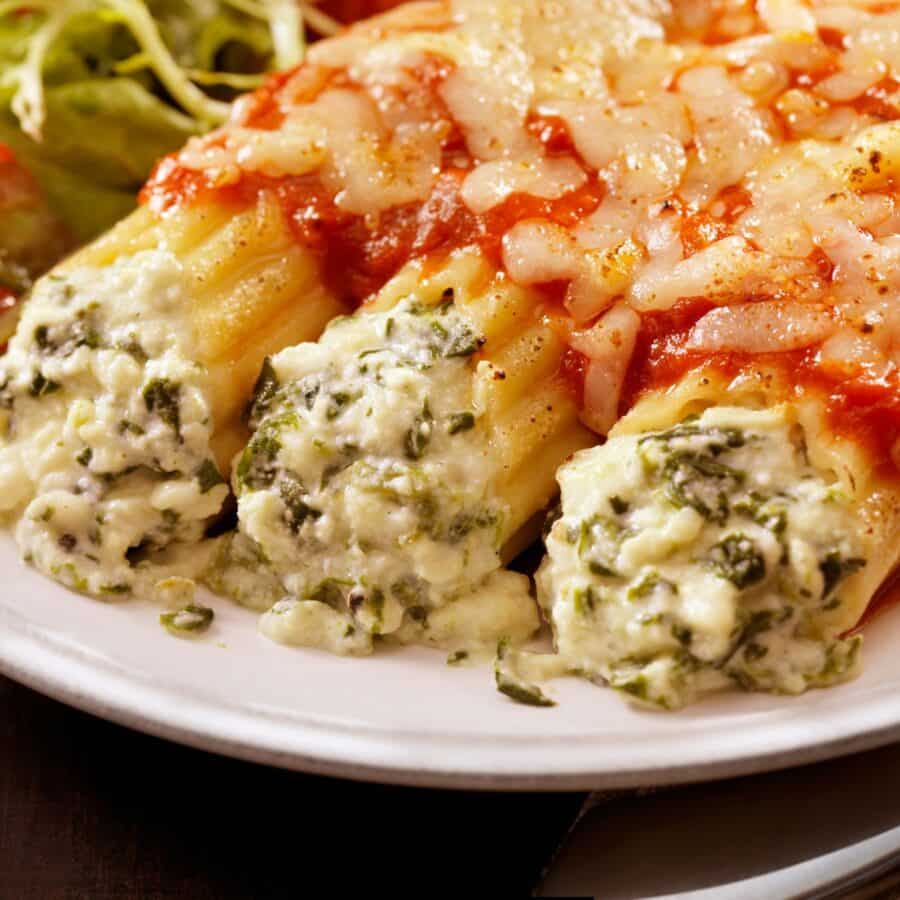 Close up image of three pieces of cheese manicotti covered in marinara sauce