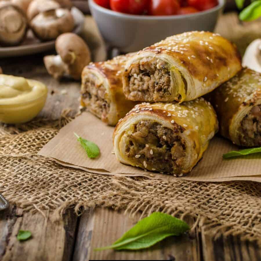 sausage rolls on a rustic surface with dipping sauces 