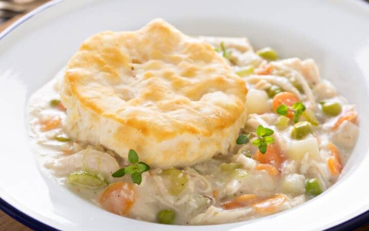 Slow Cooker Chicken Pot Pie in a white bowl with a biscuit on top